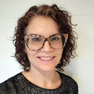 head and shoulders of Tracey Parsons smiling. She's white, with curly brown hair and glasses.