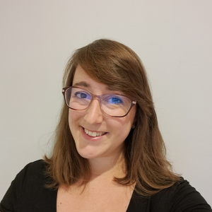 Head and shoulders of Jenny Lowey smiling. She's white with brown hair and is wearing glasses.